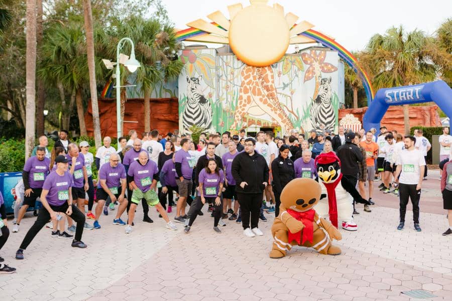 A gingerbread man and penguin character stretch with the crowd before the race.